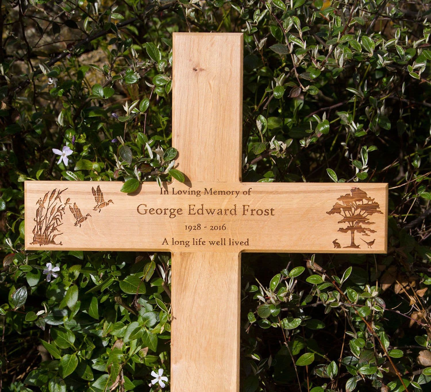 This is a brown wooden cross with inscription on it set against the ground.